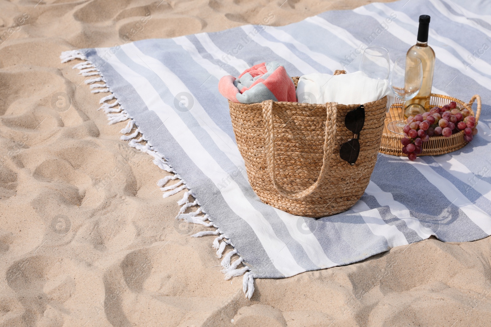 Photo of Bag, blanket, wine and other stuff for beach picnic on sand