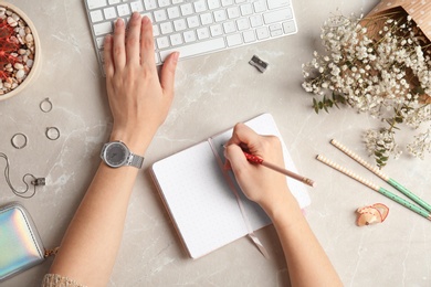 Beauty blogger writing in notebook at table, top view