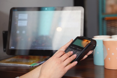 Photo of Woman using credit card machine for non cash payment in cafe, closeup. Space for text