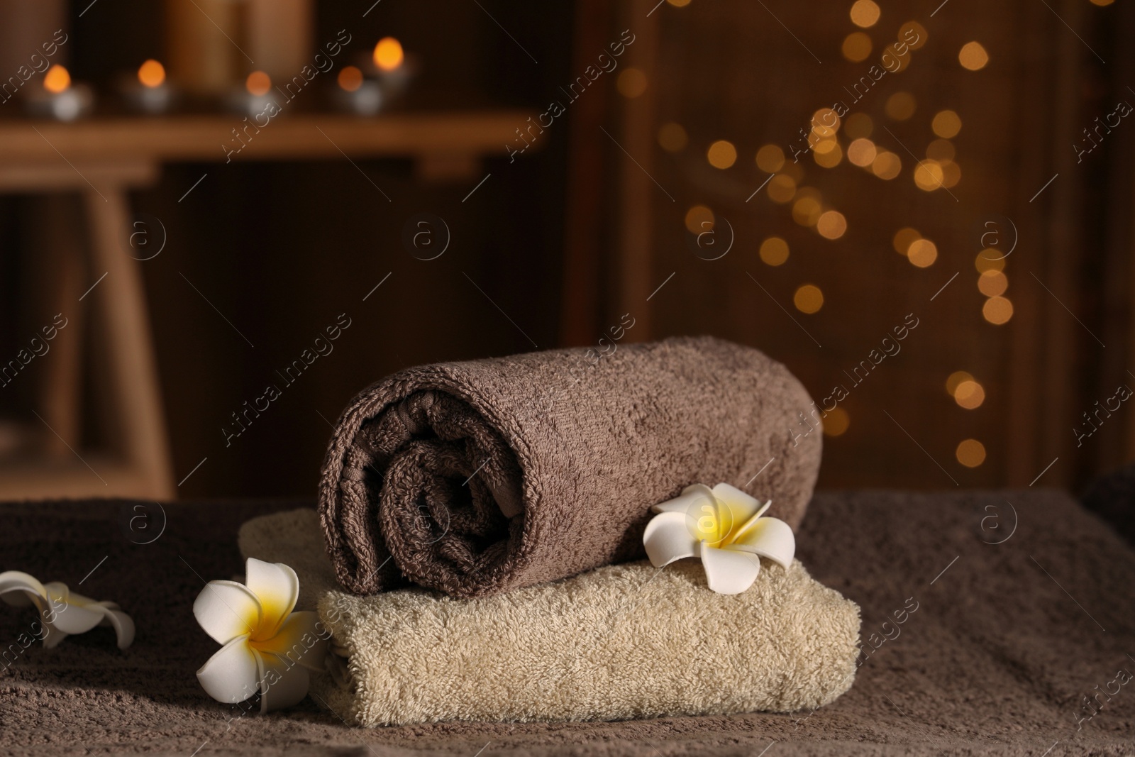 Photo of Spa composition with towels and plumeria flowers on massage table in wellness center