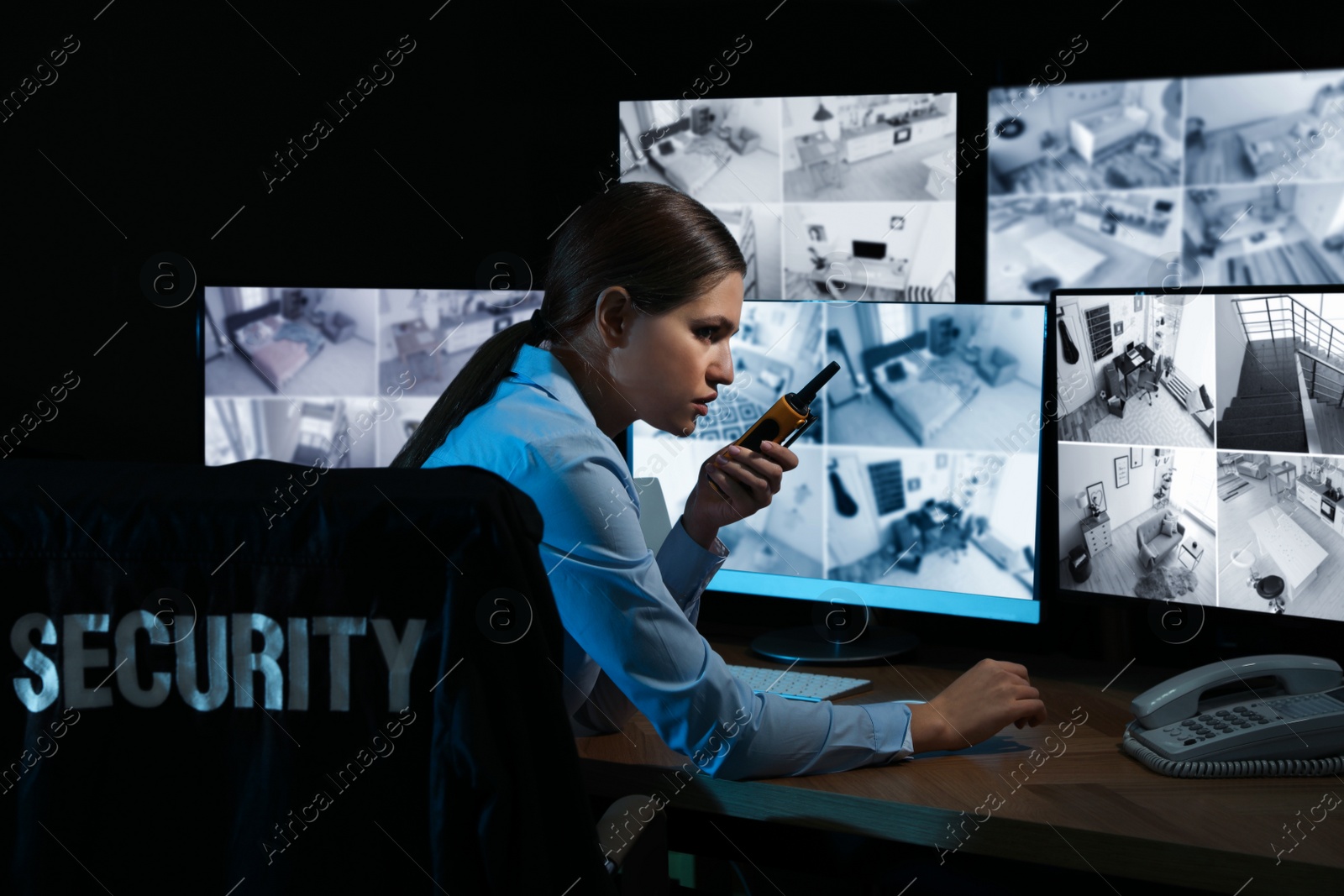 Photo of Security guard with portable transmitter monitoring modern CCTV cameras at night