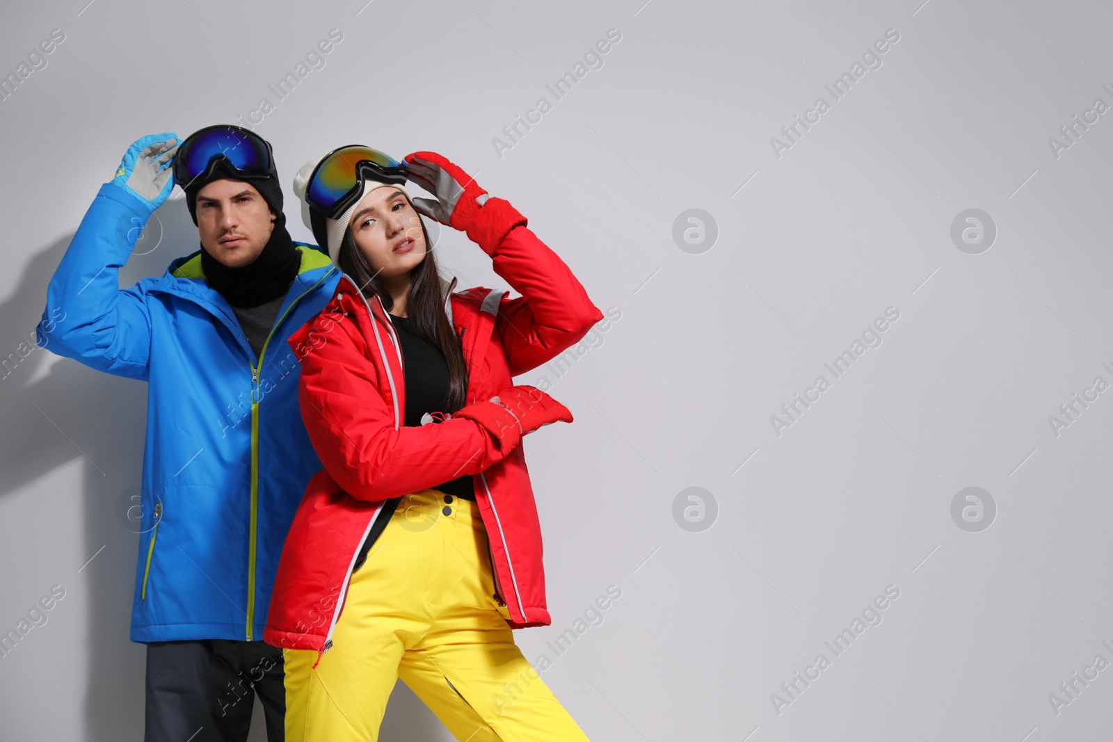 Photo of Couple wearing stylish winter sport clothes on light grey background. Space for text