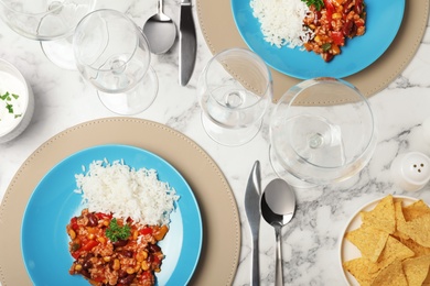 Photo of Tasty chili con carne served with rice on marble table. Dinner in restaurant