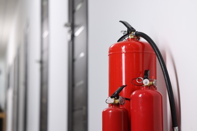 Photo of Fire extinguishers in hall, closeup. Space for text