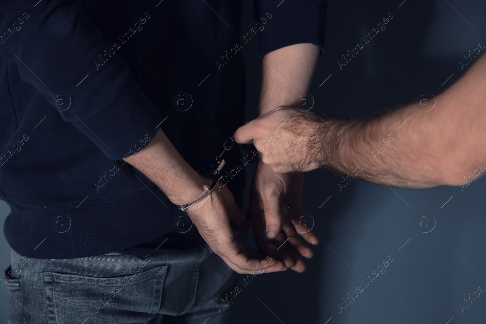 Photo of Man putting handcuffs on drug dealer, closeup view