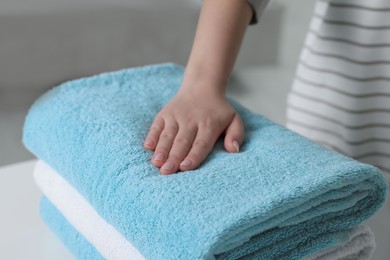 Photo of Woman touching soft light blue towel indoors, closeup
