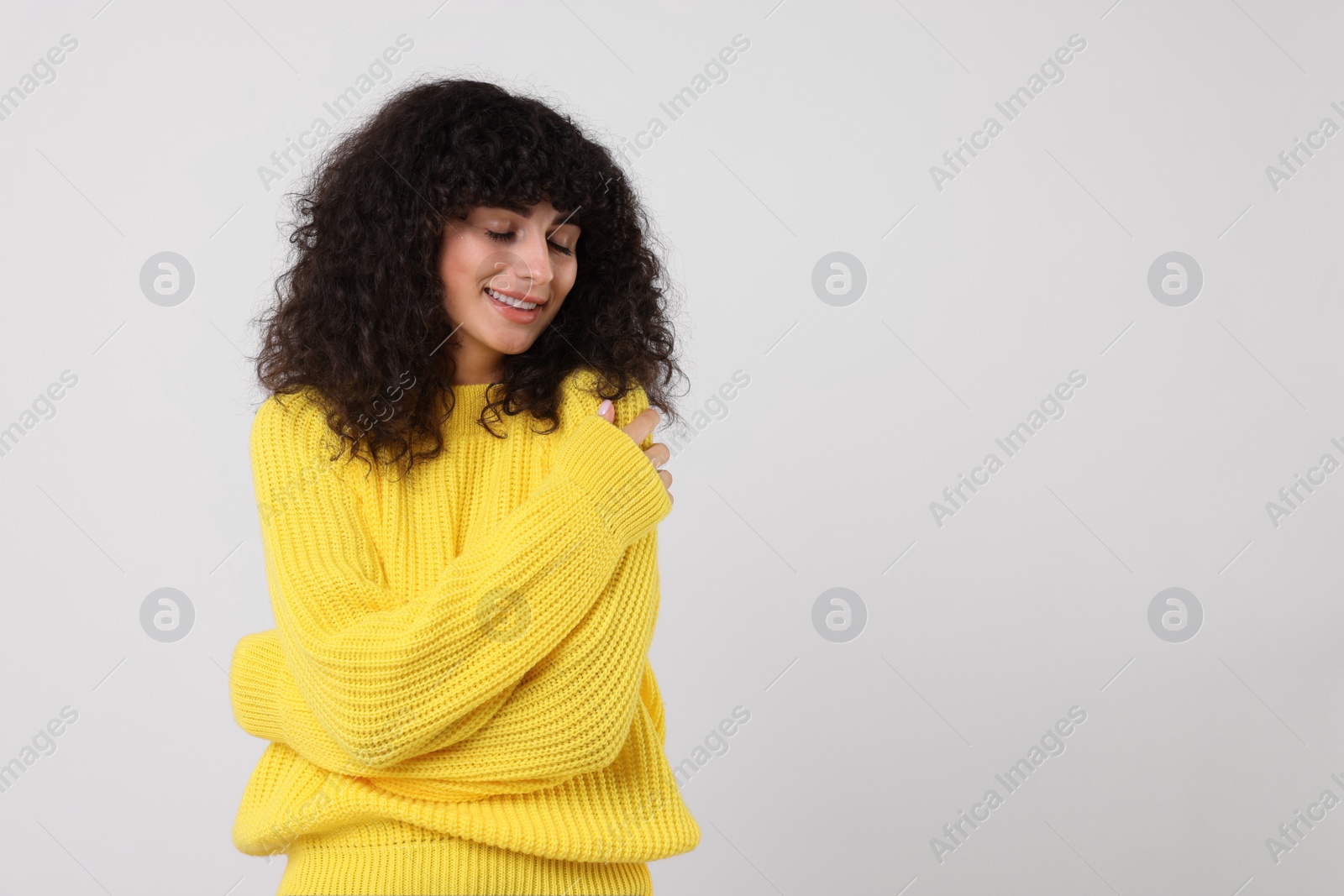 Photo of Happy young woman in stylish yellow sweater on white background, space for text