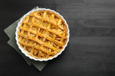 Photo of Tasty homemade quince pie on black wooden table, top view. Space for text