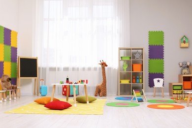 Child`s playroom with different toys and furniture. Cozy kindergarten interior