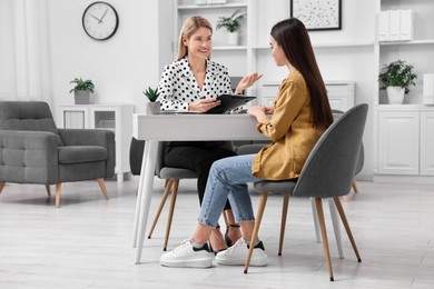 Psychologist working with teenage girl at table in office