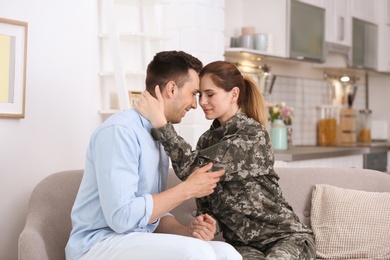 Woman in military uniform with her husband on sofa at home