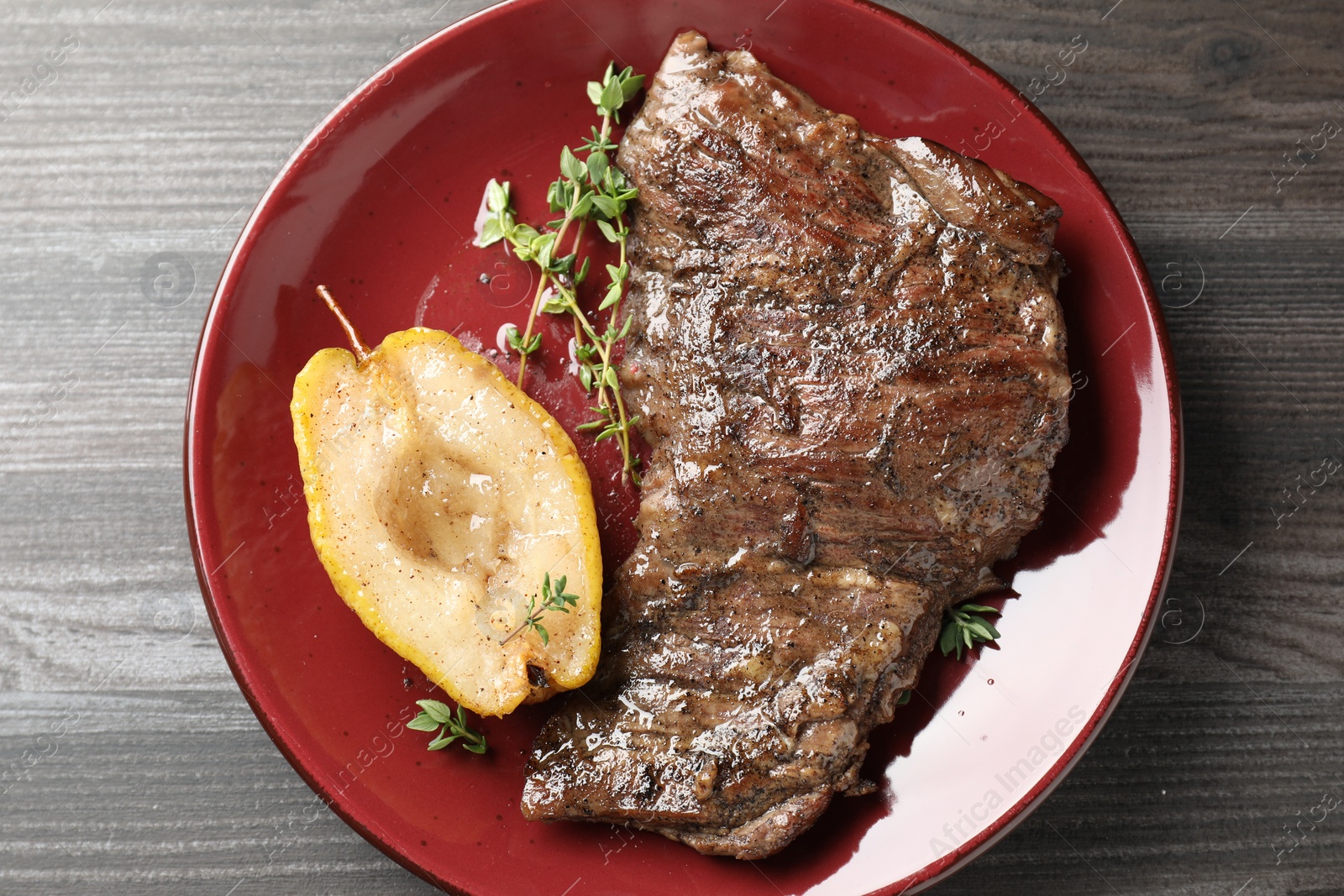 Photo of Delicious roasted beef meat, caramelized pear and thyme on grey wooden table, top view