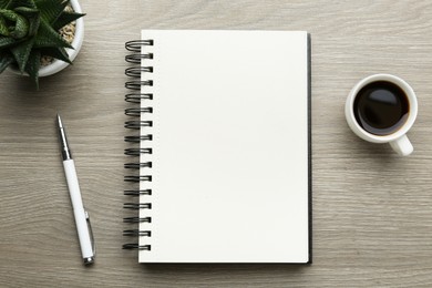 Flat lay composition with open notebook on light wooden table. Space for text