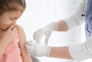 Doctor vaccinating little girl in hospital