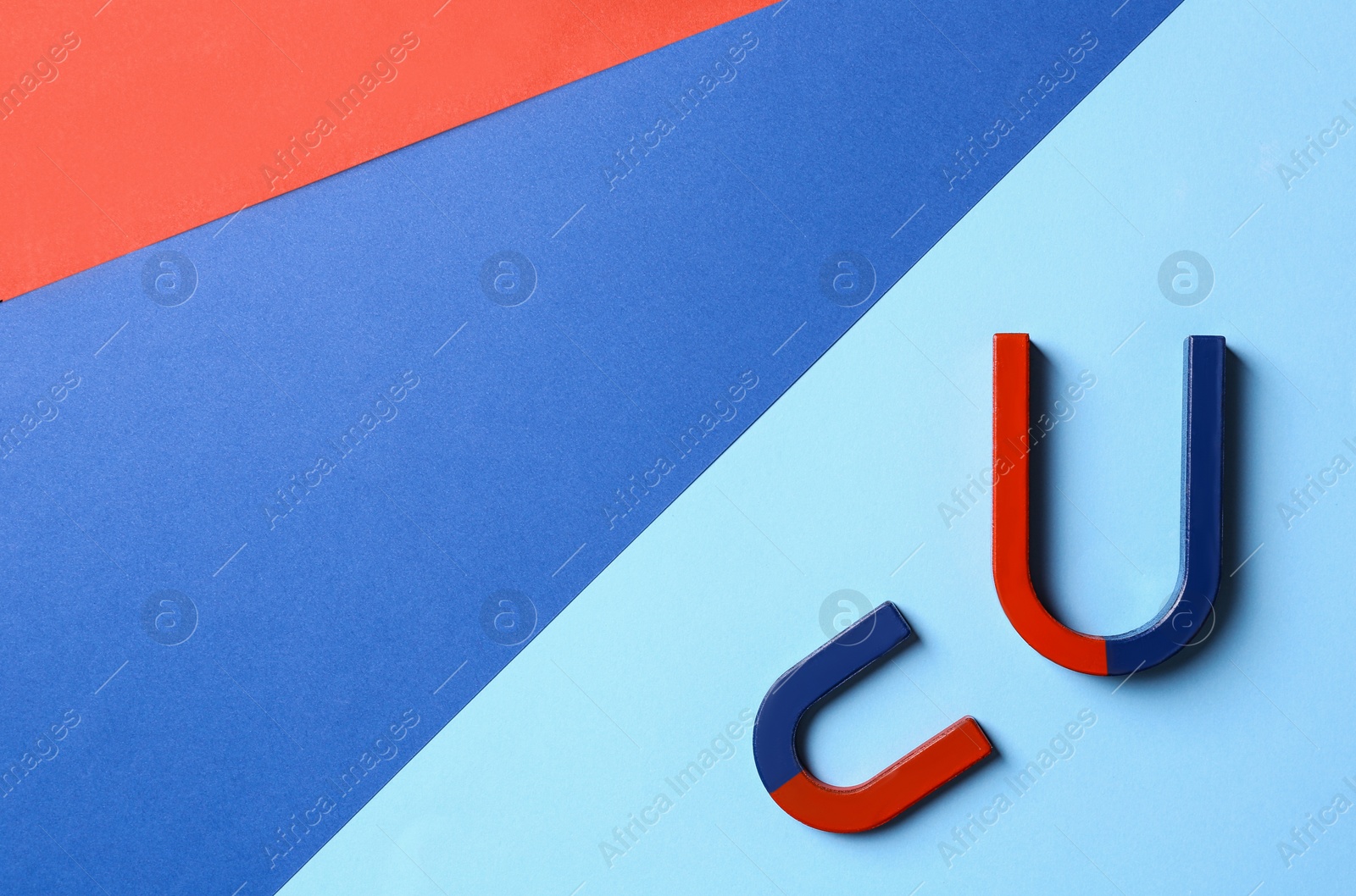 Photo of Red and blue horseshoe magnets on color background, flat lay. Space for text