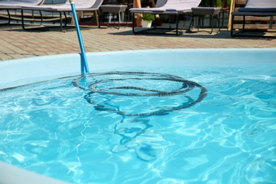 Cleaning outdoor swimming pool with underwater vacuum