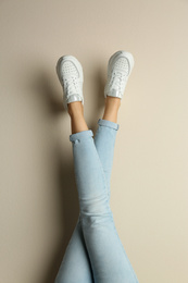 Woman wearing sneakers on beige background, closeup