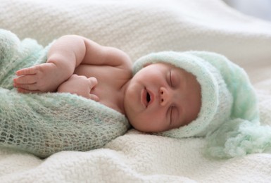 Photo of Cute newborn baby in warm hat sleeping on white plaid