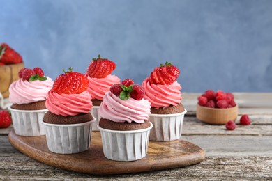 Photo of Sweet cupcakes with fresh berries on wooden table. Space for text