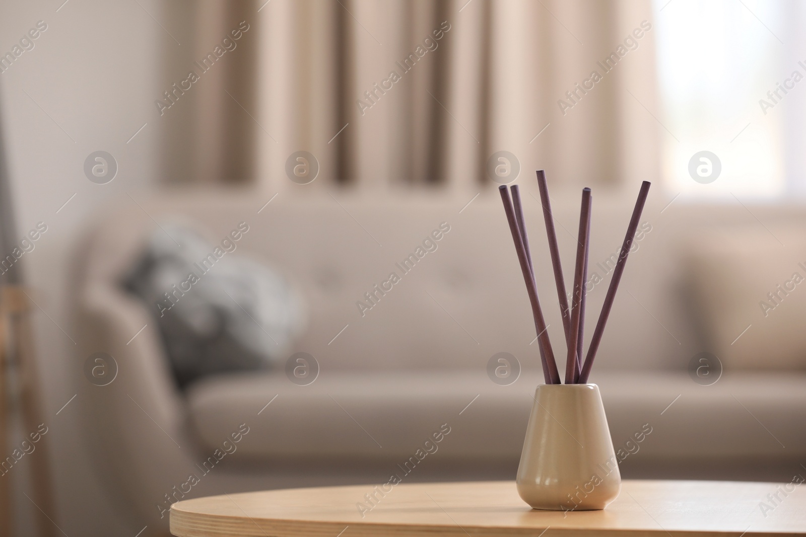 Photo of Reed air freshener with essential oil on table indoors. Space for text