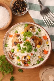 Photo of Bowl of delicious rice with vegetables on wooden table, flat lay