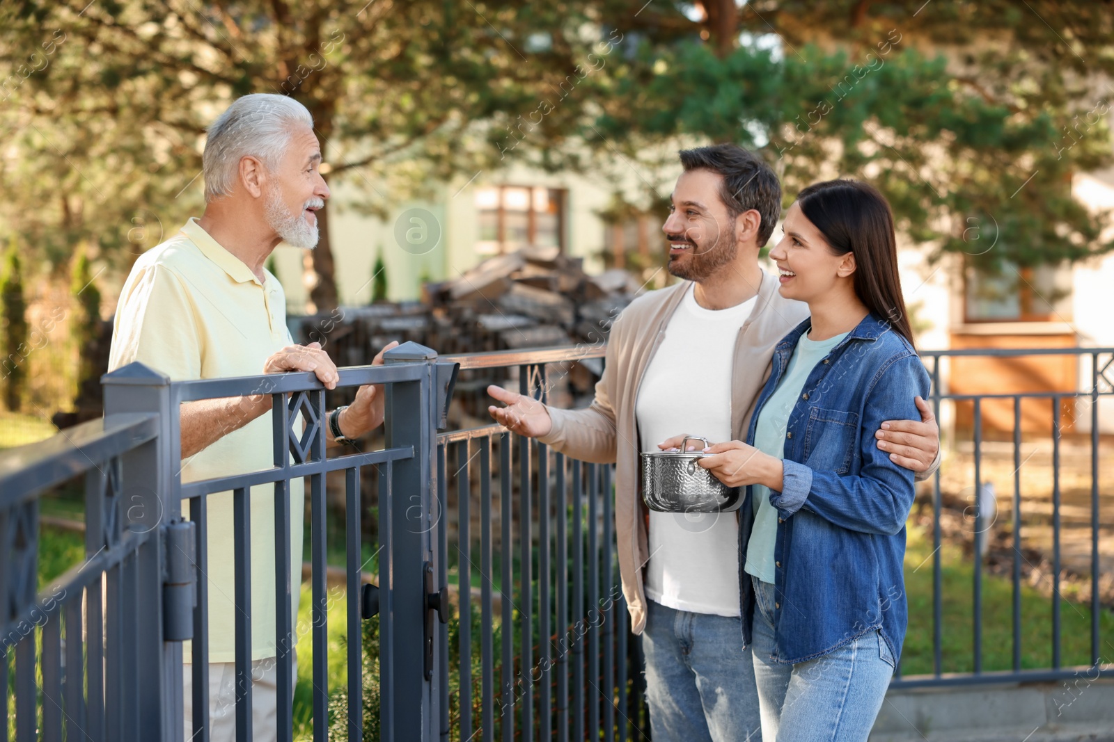 Photo of Friendly relationship with neighbours. Happy couple and senior man near fence outdoors