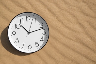 Photo of Stylish clock on sand in desert, top view. Space for text