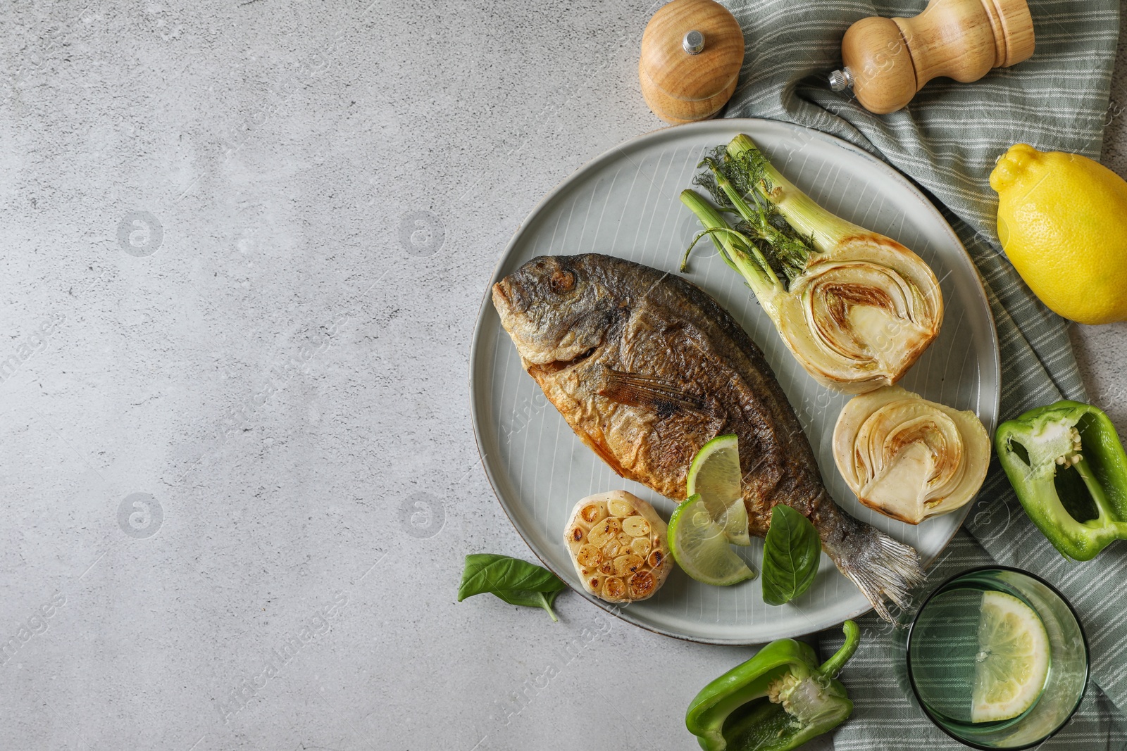 Photo of Delicious dorado fish with vegetables served on light grey table, flat lay. Space for text