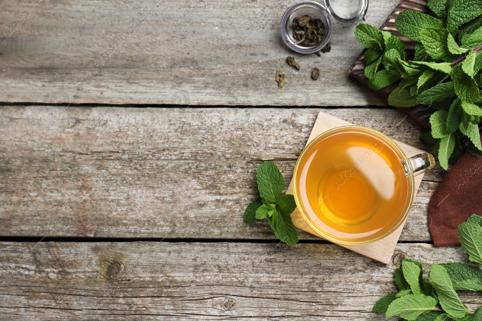 Photo of Cup of hot aromatic mint tea on wooden table, flat lay. Space for text