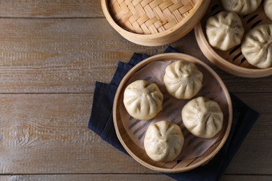 Photo of Delicious bao buns (baozi) on wooden table, flat lay. Space for text
