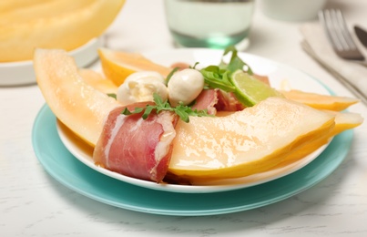 Photo of Plate with melon and prosciutto appetizer on light table