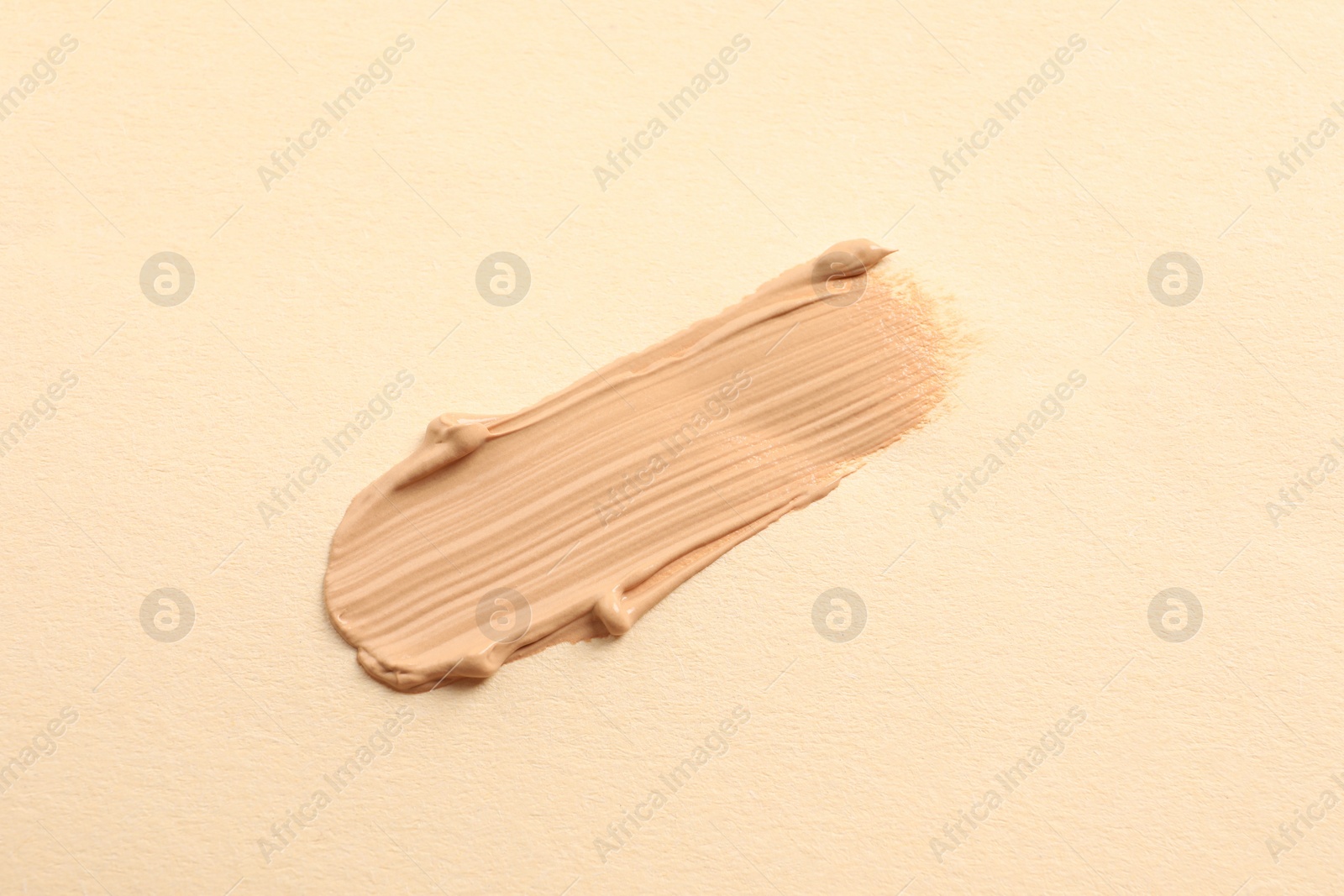 Photo of Smear of skin foundation on beige background, top view