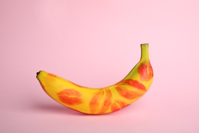Photo of Fresh banana with red lipstick marks on pink background. Oral sex concept