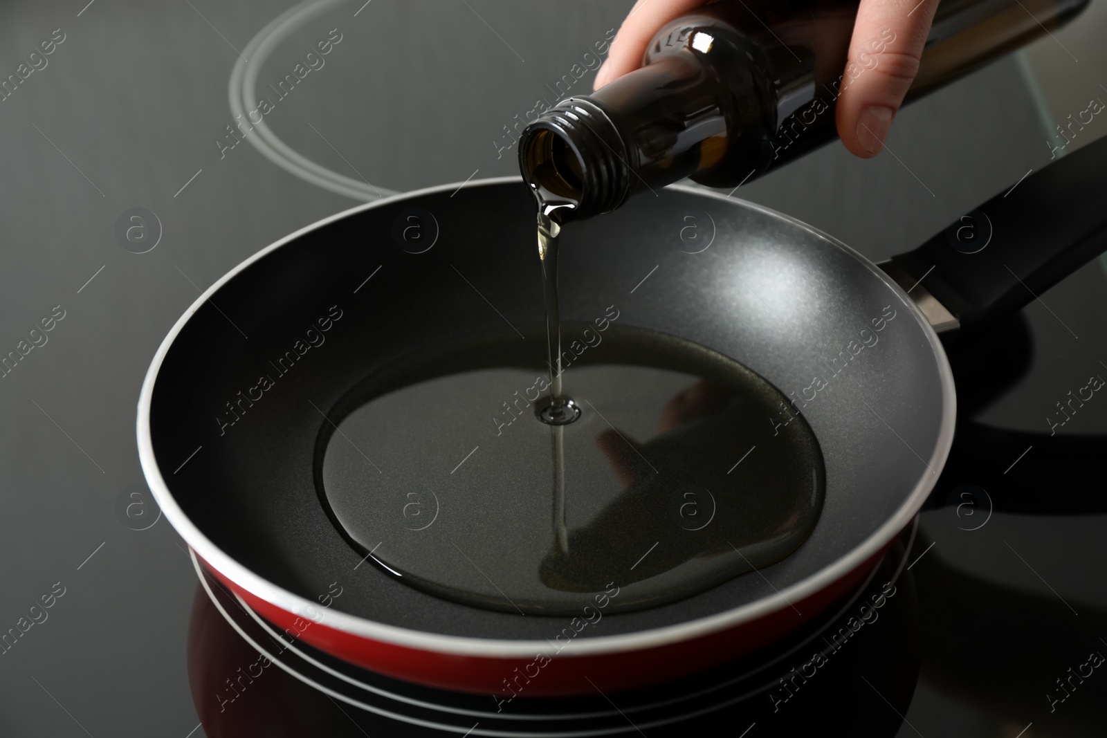 Photo of Woman pouring cooking oil from bottle into frying pan, closeup