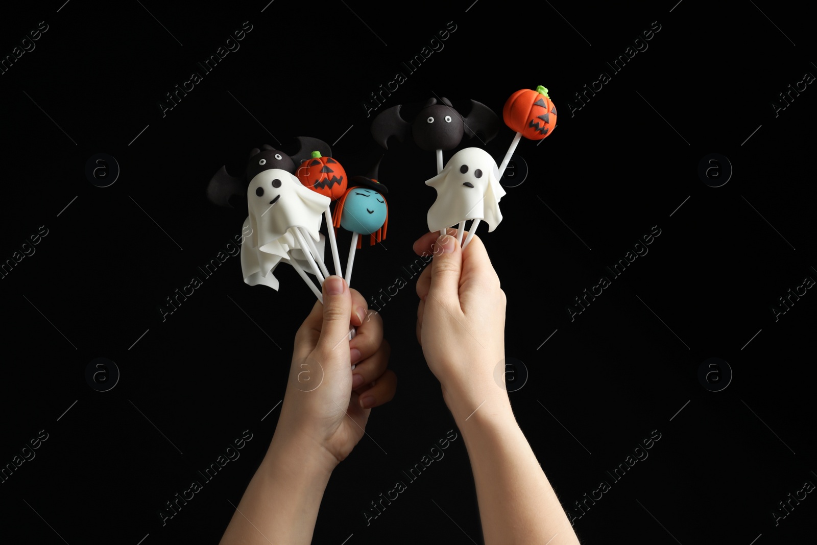 Photo of Woman with delicious cake pops on black background, closeup. Halloween celebration
