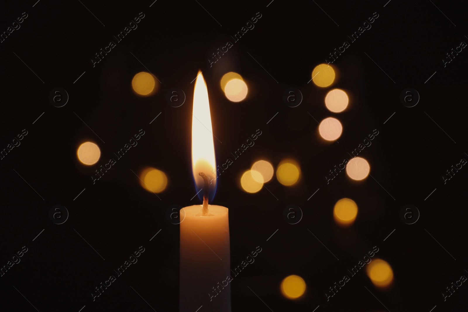 Photo of Wax candle burning on blurred background, closeup