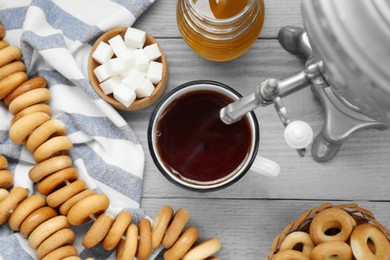 Photo of Flat lay composition with delicious ring shaped Sushki (dry bagels) and mug of tea on light grey wooden table