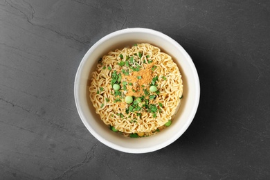 Cup of instant noodles on grey background, top view