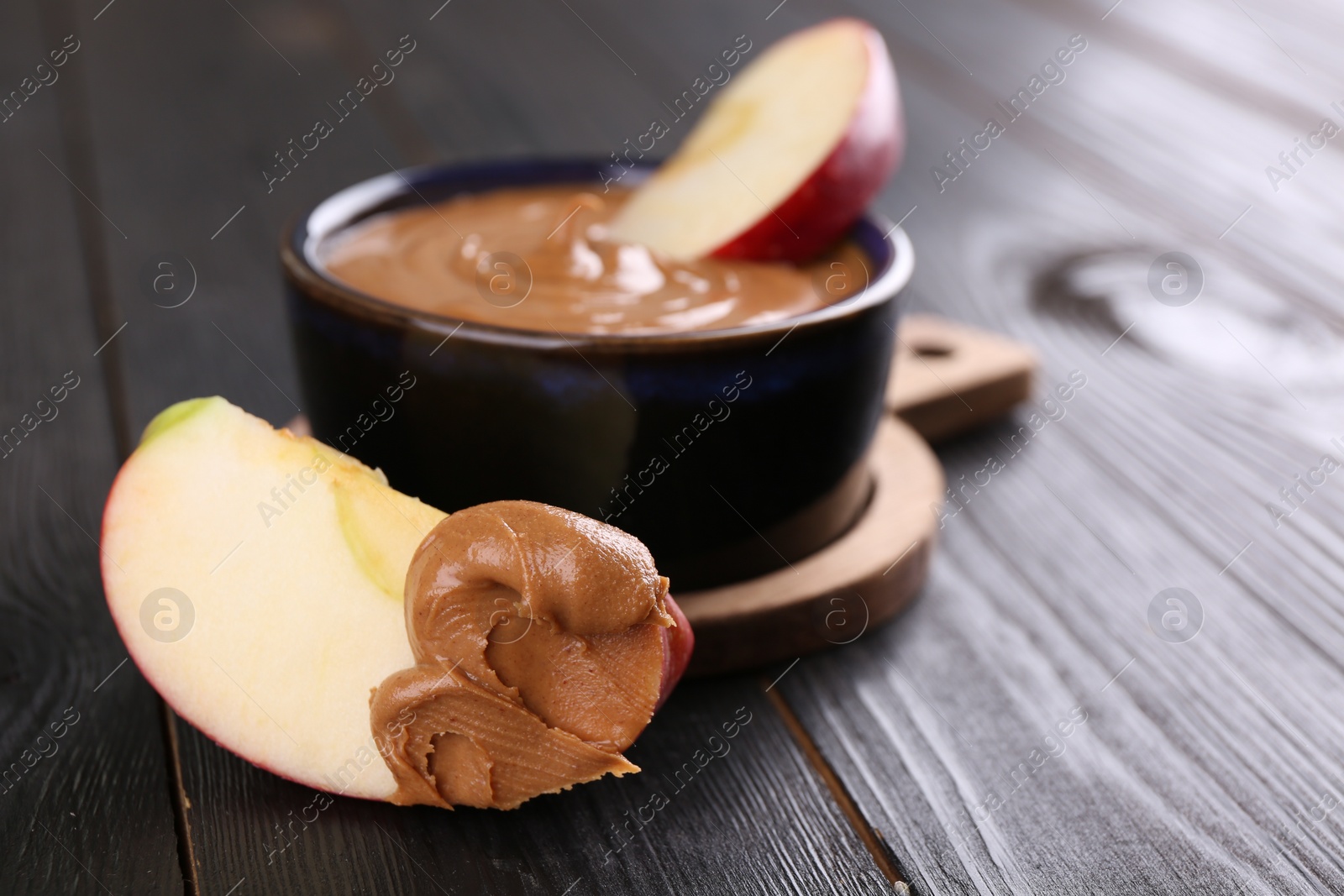 Photo of Slices of fresh apple with peanut butter on wooden table, closeup. Space for text