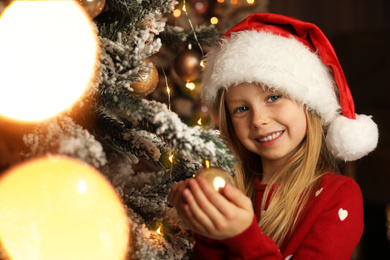 Photo of Cute little child near Christmas tree at home