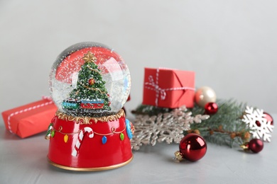 Photo of Beautiful snow globe, gifts and Christmas decor on light grey stone table