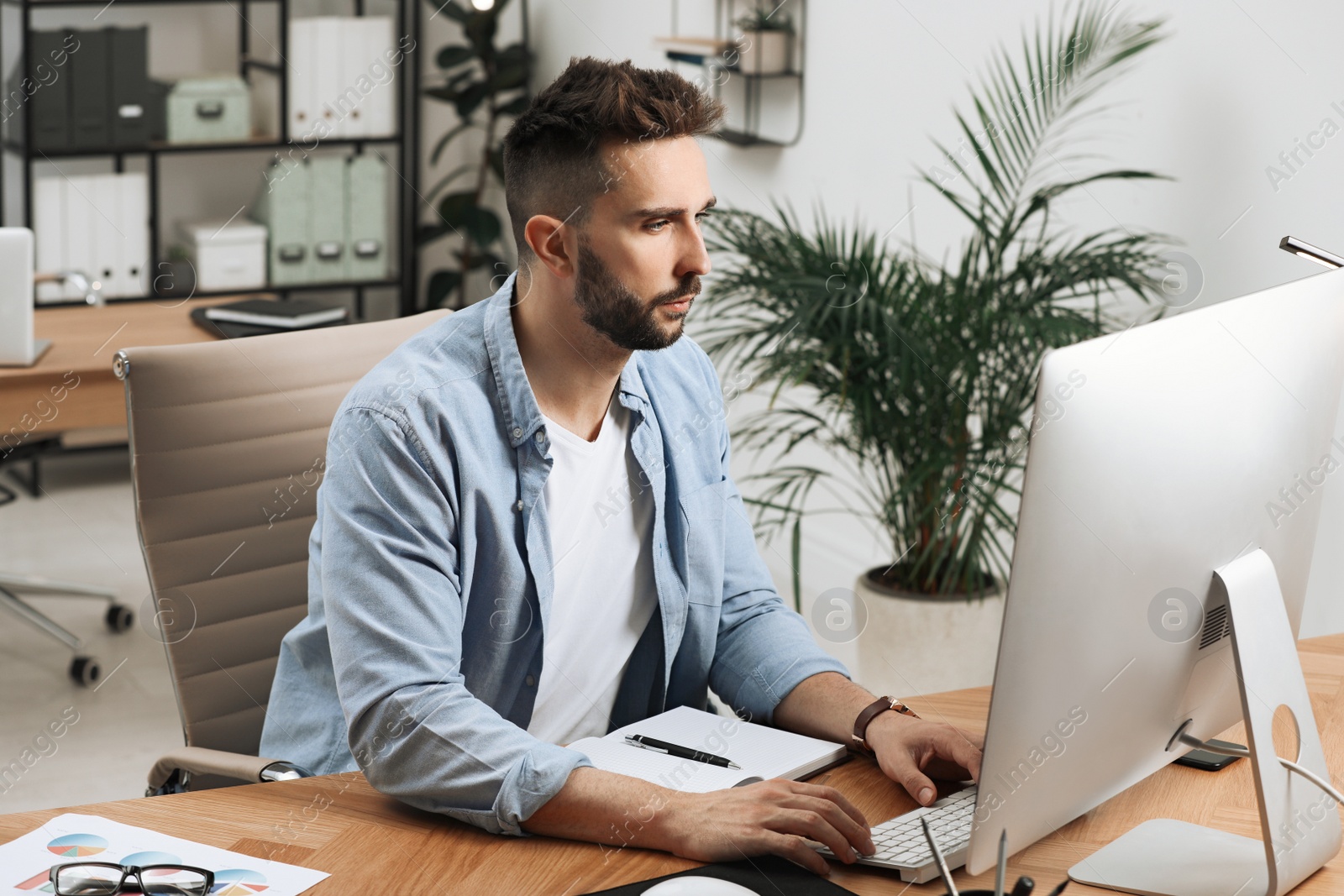 Photo of Man working on computer at table in office