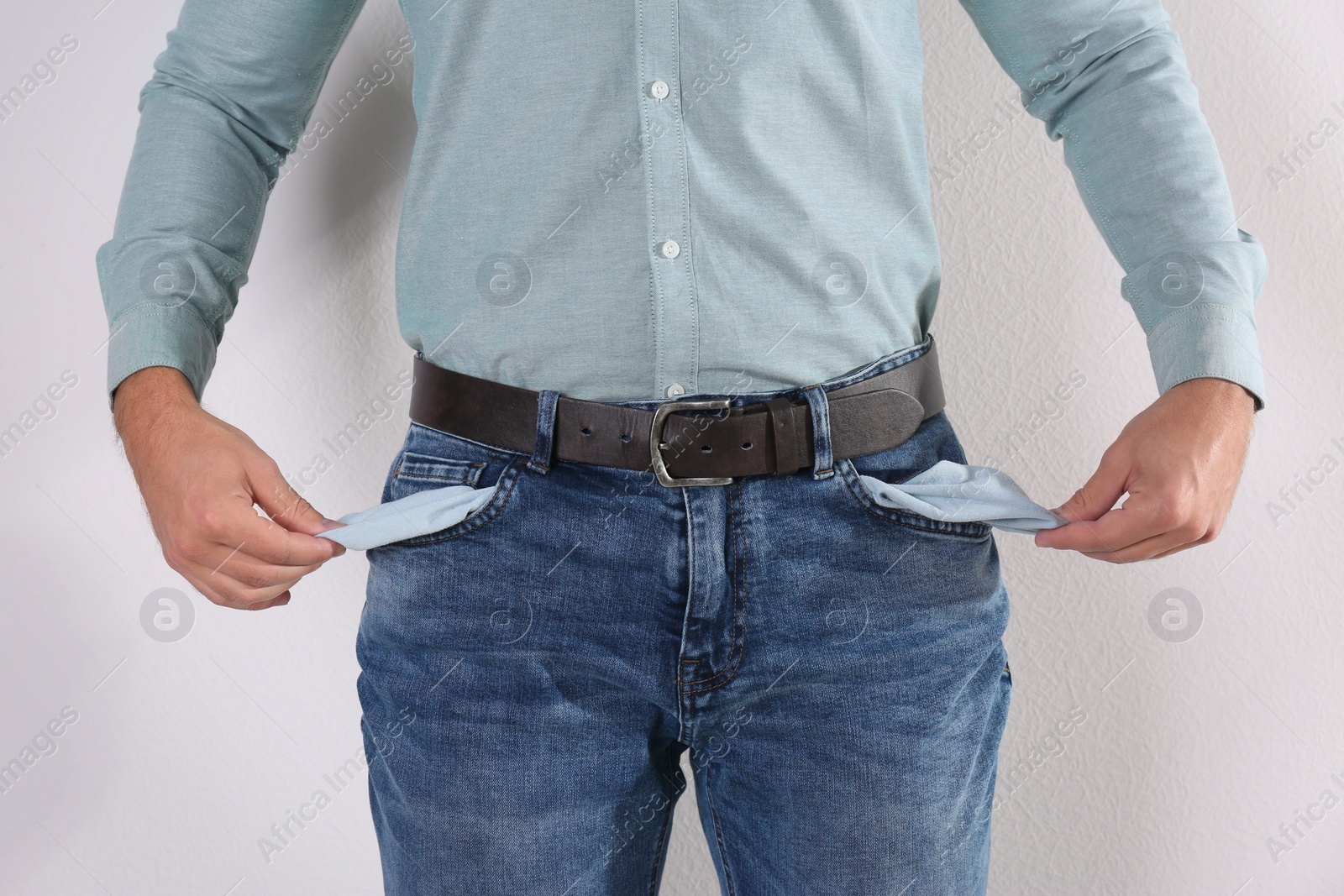 Photo of Man showing empty pockets on light background, closeup