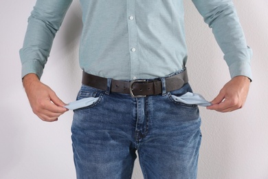 Man showing empty pockets on light background, closeup