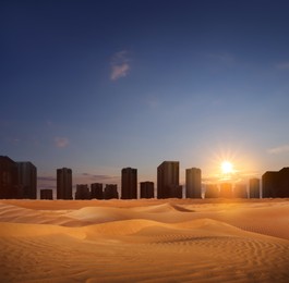Sandy desert and silhouette of city on horizon at sunset 