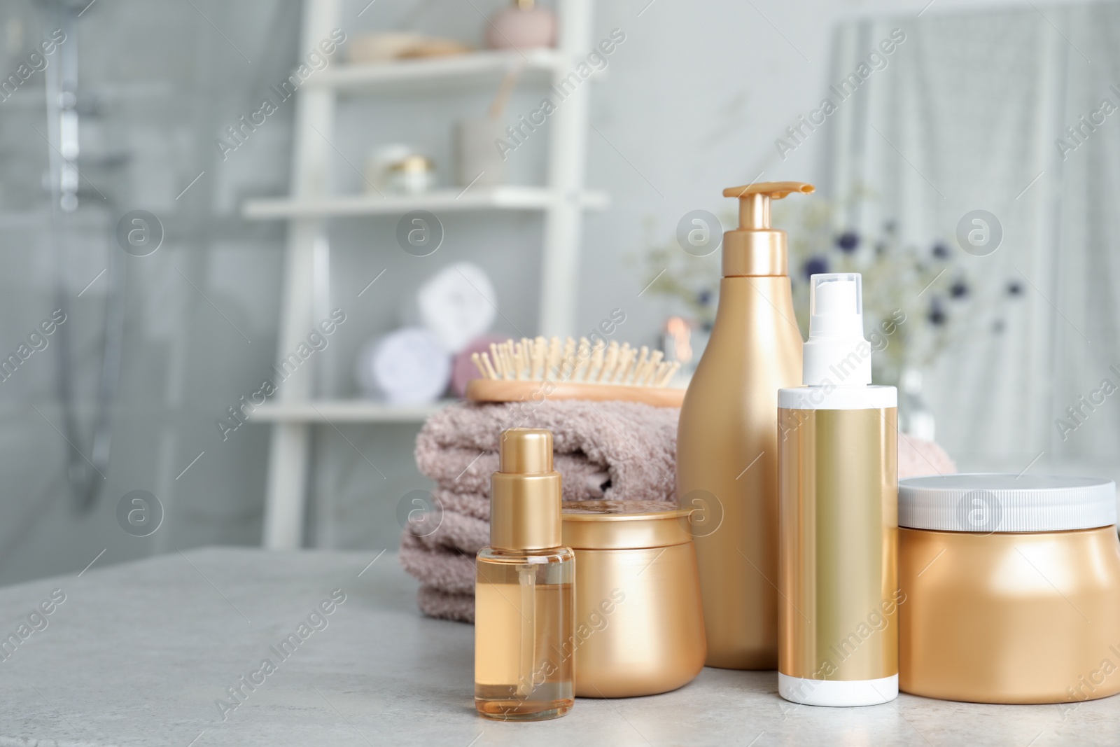 Photo of Set of hair care cosmetic products on light grey stone table in bathroom. Space for text