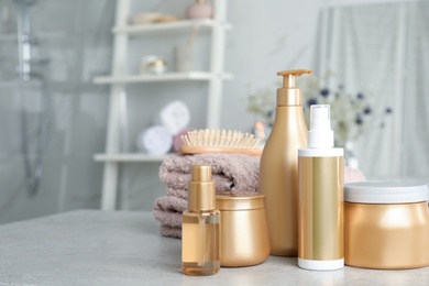 Photo of Set of hair care cosmetic products on light grey stone table in bathroom. Space for text