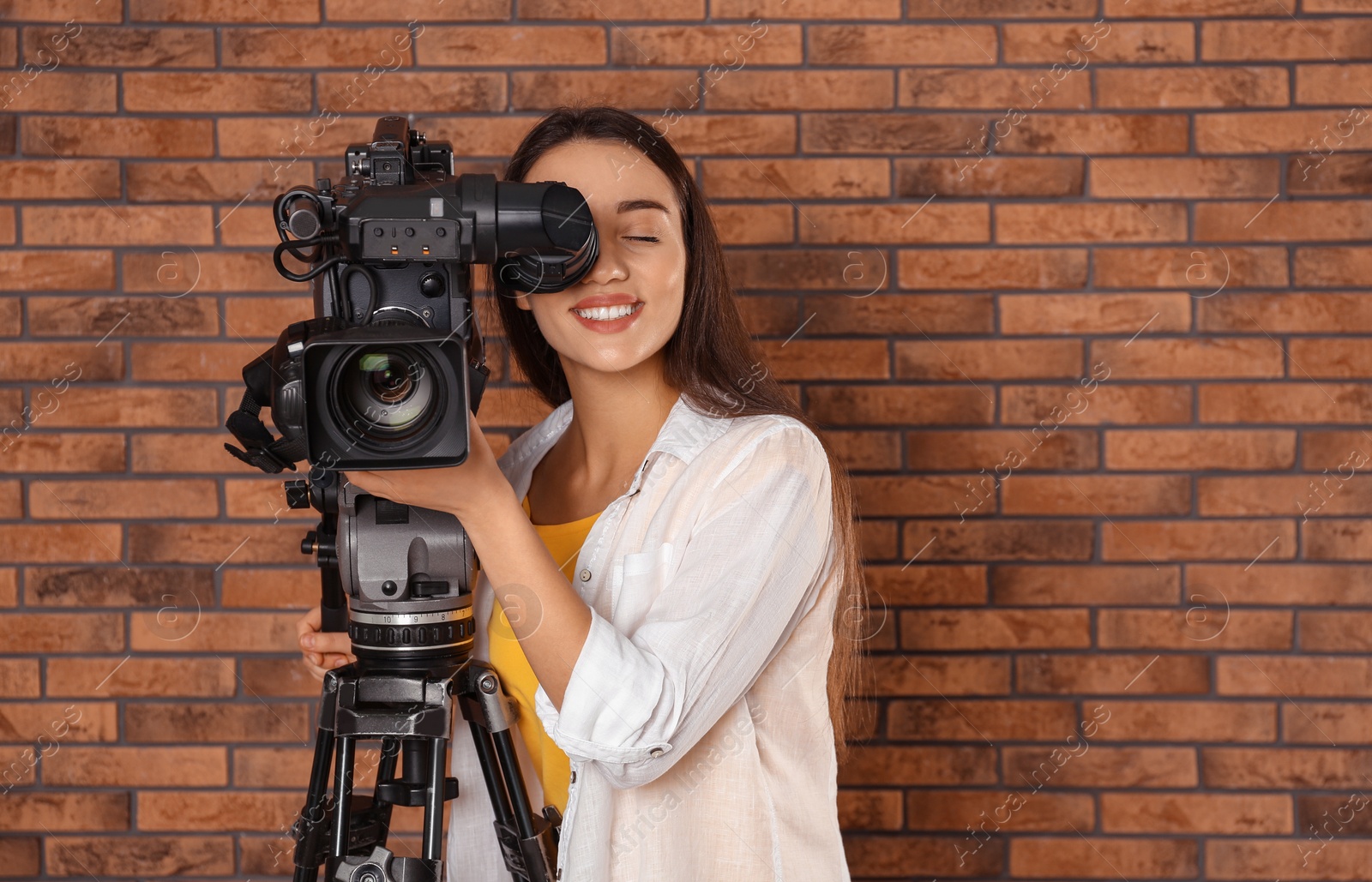 Photo of Operator with professional video camera near brick wall