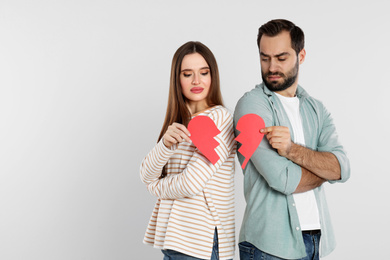 Photo of Couple with torn paper heart on light background. Relationship problems