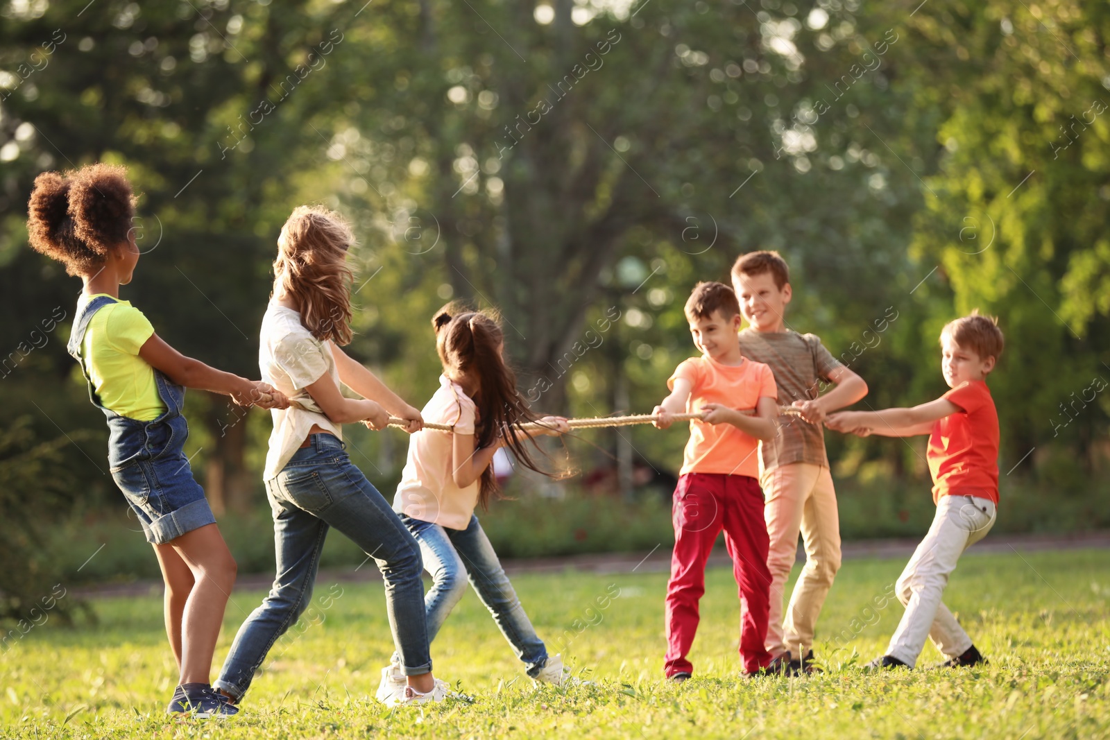 Photo of Cute little children playing with rope outdoors on sunny day